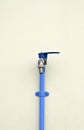Locked faucet with blue PVC pipe on concrete wall