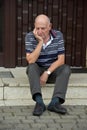 Locked out senior man sitting in front of his house