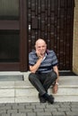 Locked out senior man sitting in front of his house