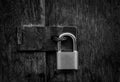 Locked padlock with chain at gray wooden door. black and white