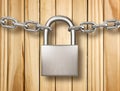 Locked padlock with silver chains on wood background