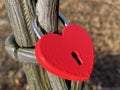 Locked red heart-shaped padlock on the fence of a small pedestrian bridge next to Au Castle and a park by Lake Au Ausee