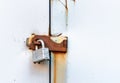 Locked simple metal padlock hanging on rusted hasp on metal doors. Royalty Free Stock Photo