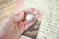locket on the woman hand- holding beautiful luxury round locket on letters and photo background. emories concept.