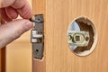 Locksmith secures the latch into the wood interior door with 2 screws Royalty Free Stock Photo