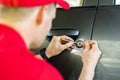 Locksmith opening car door with lockpicker Royalty Free Stock Photo