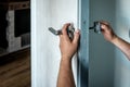 Locksmith repairing the doorknob. closeup of worker's hands installing new door locker Royalty Free Stock Photo