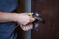 Locksmith replacing door lock to new after losing keys. Robbery protection, safety improvement. Repairman or workman changing or Royalty Free Stock Photo