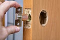 Locksmith shoves the latch Into hole of interior door