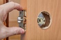 Carpenter shoves latch assembly of door knob through the edge bore