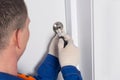 A locksmith in uniform, unscrews the bolt on the front door to close the room from the inside Royalty Free Stock Photo