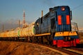 Locomotive pulls cisterns in the morning sun.