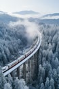 A locomotive pulls a passenger train along a winding road among the winter forest and mountains.