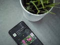Modern minimalist office workspace with black mobile smartphone with PlantSnap app play store page on marble background