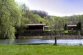 A lodge by the lake in a green cozy park. A beautiful green park with a view of the lake is a cozy little house.