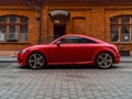 Red Audi TT in front of old small red brick building