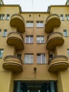 Upward view to yellow old tenement house with symmetrical balconies and lamp in center