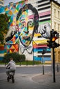 Lodz, Poland: Rear view of a man riding a small bicycle bike against a picture painted as a street art of the