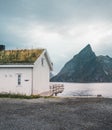 Lofoten Islands Norway - September 2018: House with traditional grass roof and mountains in the background on a cloudy Royalty Free Stock Photo