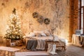 Loft apartments, brick wall with candles and Christmas tree wreath. Bed in the bedroom, high large Windows