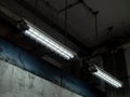 Loft industrial ceiling lights covered with wire mesh hanging under ceiling in old white building.