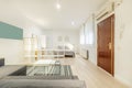 Loft-style apartment with empty white wooden divider shelves, gray fabric sofa, armored access door and bedroom with a gray box in Royalty Free Stock Photo