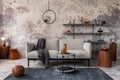 Loft style of modern apartment with grey design sofa, coffee table, bookstand, pedant lamp, carpet, decoration and elegant