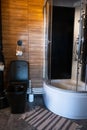 Loft-style toilet and shower, dark interior, combination of black and wood. Black toilet bowl, cozy knitted rug