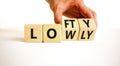 Lofty or lowly symbol. Concept words Lofty Lowly on wooden block. Beautiful white table white background. Businessman hand.