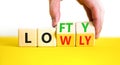 Lofty or lowly symbol. Concept words Lofty Lowly on wooden block. Beautiful yellow table white background. Businessman hand.