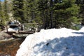 A log bridge crossing Glacier Creek with snowbanks covering the trail on Glacier Gorge Trail in Colorado