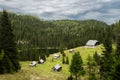 Log cabins and a mountain lake in the mountains of the Slovenian Alps on the peak Planina Blato on sunny day with clouds