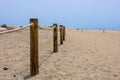 Log fence in a sandy shore on a sunny morning Royalty Free Stock Photo