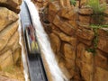 Log flume ride steep drop into artificial canyon with waterfall speed blur Royalty Free Stock Photo