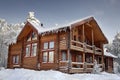 Log home winter with large windows, balcony and porch, daytime. Royalty Free Stock Photo