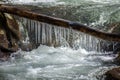 Log with icicles over a river Royalty Free Stock Photo