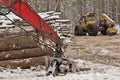 Log or Logging Skidder and Knuckleboom loader with Freshly Harvested and piled timber logs