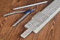 Logarithmic ruler, compasses, pencil on a wooden table. Stationery for engineers and students