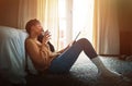 Logged into a lazy evening. a relaxed young woman drinking coffee and using a digital tablet at home.