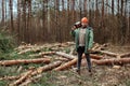 Logging, Worker in a protective suit with a chainsaw. Cutting down trees, forest destruction. The concept of industrial