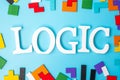 LOGIC text with colorful wood puzzle pieces, geometric shape block on blue background. Concepts of logical thinking, Conundrum,