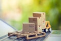 Logistic and cargo freight concept: Fork-lift a truck moves a paper box on notebook keyboard in the natural green background.