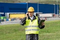 Logistician with phone and digital tablet on a background of logistic center.