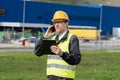 Logistician with phone and digital tablet on a background of logistic center.