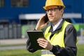 Logistician with phone and digital tablet on a background of logistic center