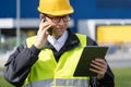 Logistician with phone and digital tablet on a background of logistic center