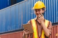 The logistics female staff is standing in front of colorful containers at habour warehouse and talking on phone. Supply chain and Royalty Free Stock Photo