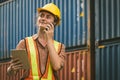 The logistics female staff is standing in front of  colorful containers at habour warehouse and talking on phone. Supply chain and Royalty Free Stock Photo