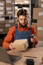 Logistics and transport worker in a warehouse full of goods for storage and dispatch. Male employee scanning a parcel