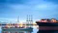 Logistics and transportation of international container cargo ship with ports crane bridge in harbor at dusk for logistics import Royalty Free Stock Photo